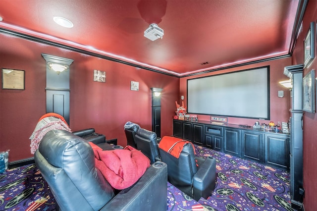 carpeted home theater room featuring crown molding