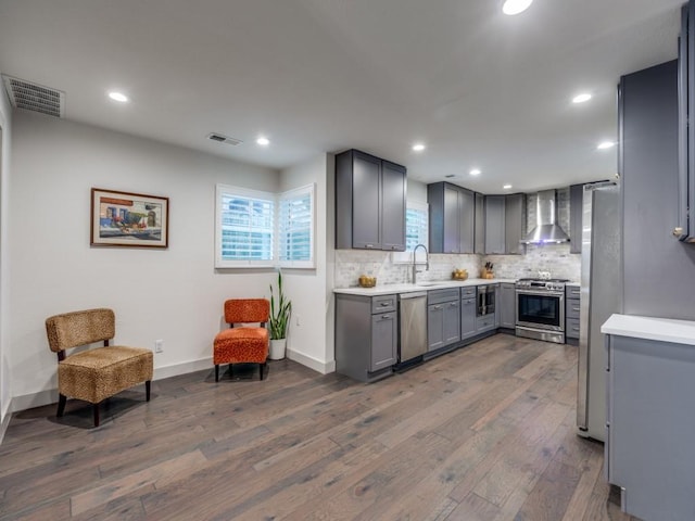 kitchen featuring gray cabinets, wall chimney range hood, sink, and appliances with stainless steel finishes