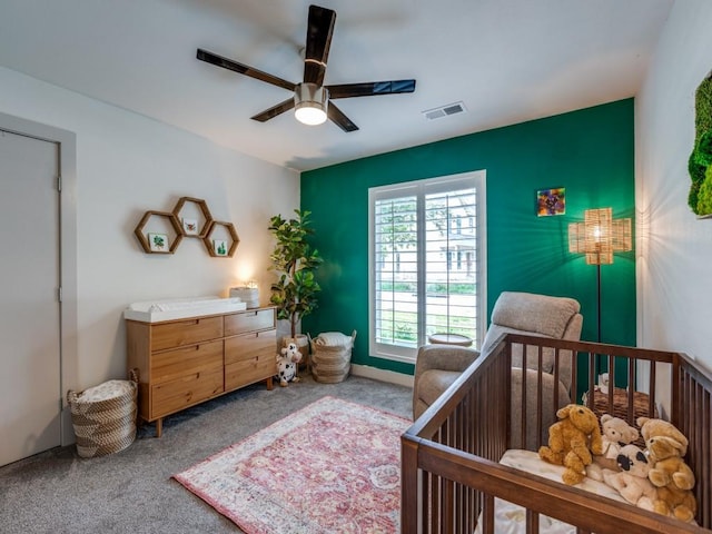 bedroom with a crib, carpet floors, and ceiling fan