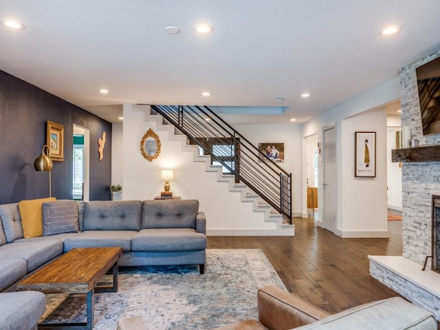 living room with a stone fireplace and hardwood / wood-style flooring