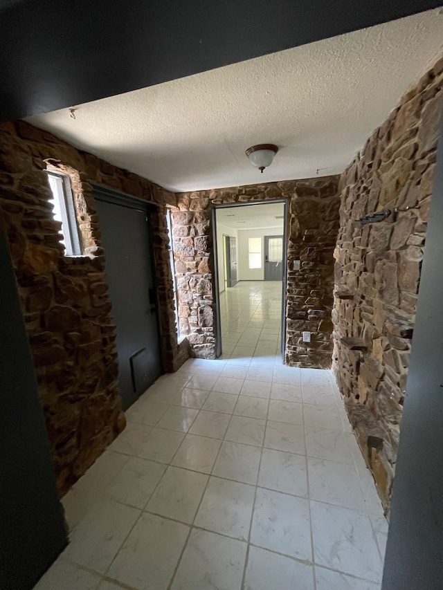 hallway with light tile patterned floors and a textured ceiling