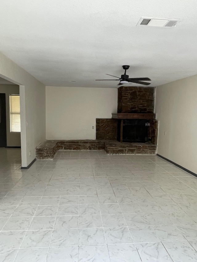 unfurnished living room with a stone fireplace and ceiling fan