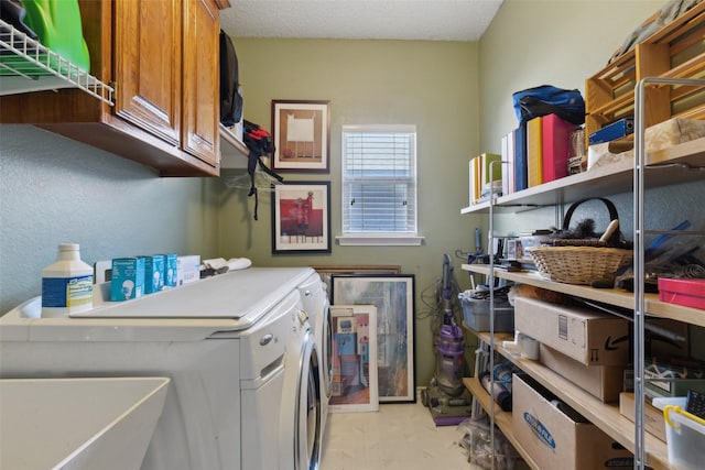 clothes washing area with cabinets, sink, a textured ceiling, and washing machine and dryer