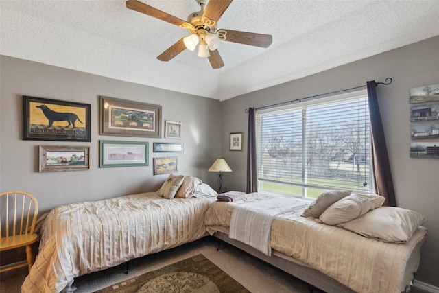 bedroom featuring ceiling fan, carpet, a textured ceiling, and lofted ceiling