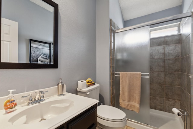 bathroom featuring toilet, vanity, and a shower with door