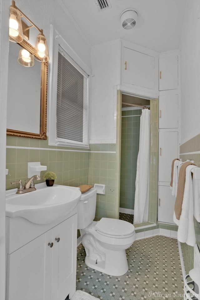 bathroom featuring vanity, toilet, walk in shower, and tile walls