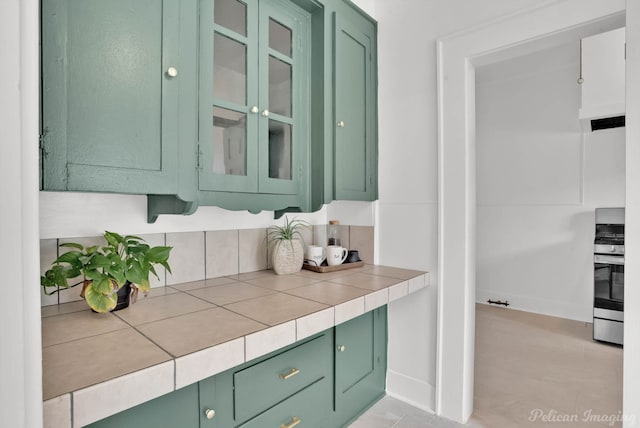 bar with green cabinets, stainless steel range, and tile counters