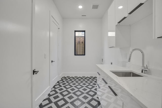 clothes washing area with cabinets and sink