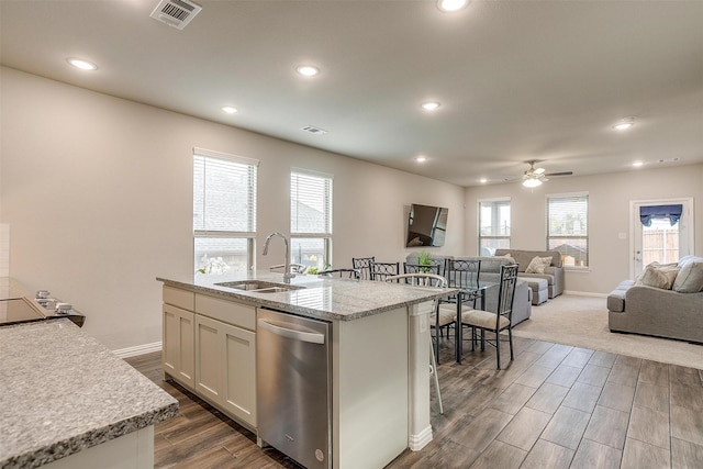 kitchen with a center island with sink, sink, stainless steel dishwasher, light stone counters, and white cabinetry