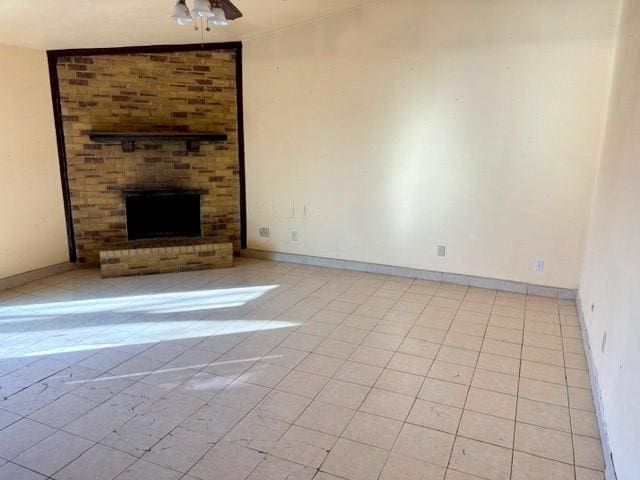 unfurnished living room with ceiling fan, a brick fireplace, and light tile patterned flooring