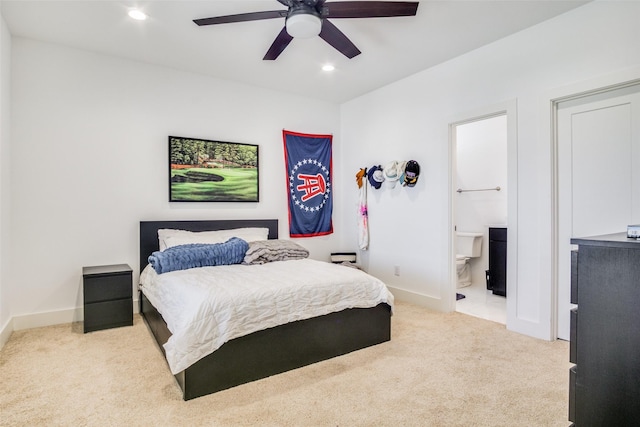 bedroom featuring ceiling fan, light colored carpet, and ensuite bathroom