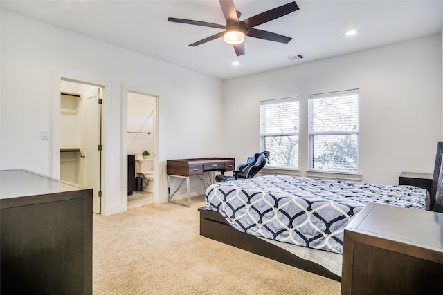 bedroom featuring light carpet, a walk in closet, ensuite bathroom, ceiling fan, and a closet