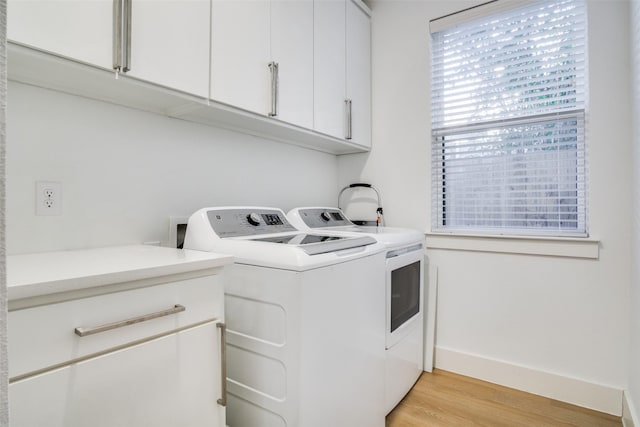 laundry area featuring washing machine and dryer, cabinets, and light wood-type flooring