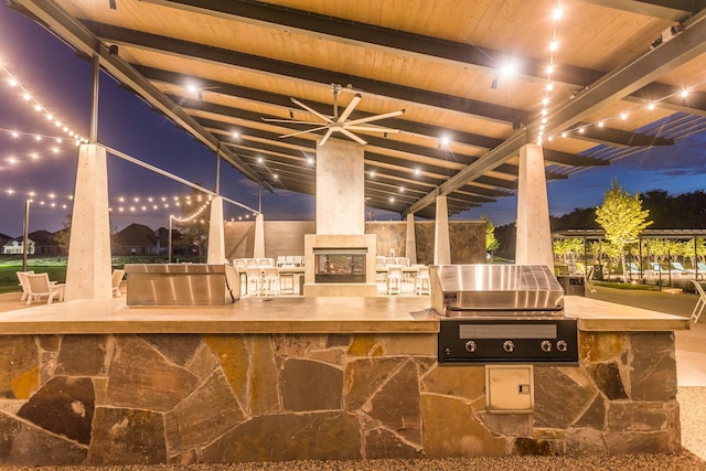 view of patio featuring a grill, an outdoor stone fireplace, and an outdoor kitchen