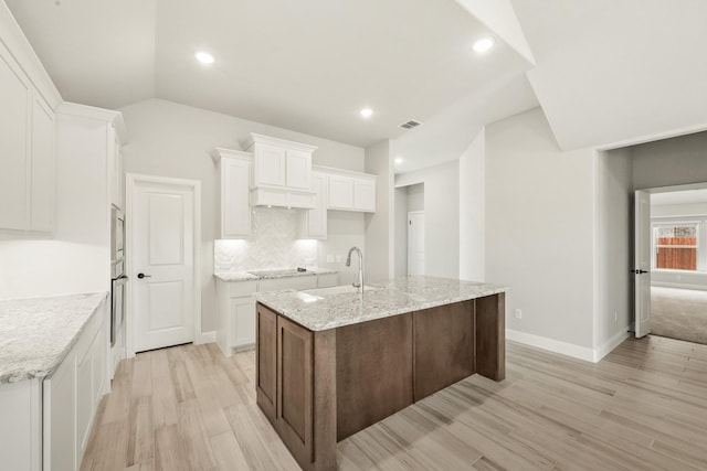489 Red Maple Rd, Waxahachie, TX 75165 - kitchen with light wood-style flooring, a sink, white cabinets, oven, and a center island with sink