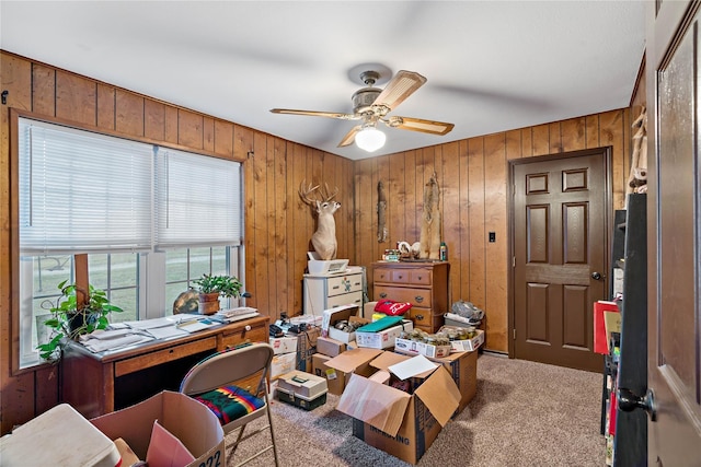 office area with carpet flooring, ceiling fan, and wooden walls