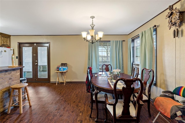 dining space with french doors, dark hardwood / wood-style floors, and an inviting chandelier