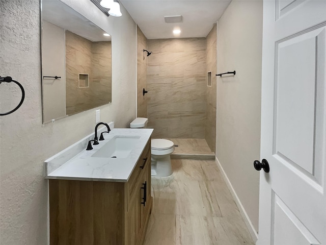 bathroom featuring tiled shower, vanity, and toilet