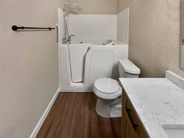 bathroom featuring hardwood / wood-style floors, a washtub, toilet, and vanity