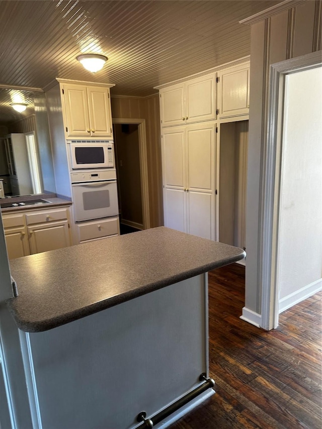 kitchen with dark countertops, white cabinets, white appliances, and dark wood-style flooring