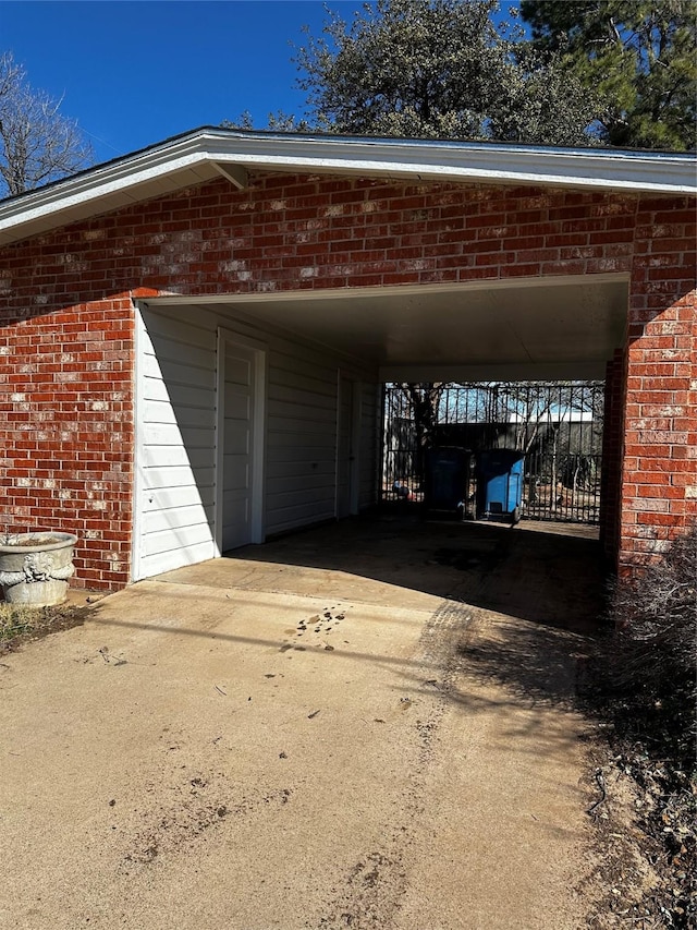 garage featuring an attached carport and concrete driveway