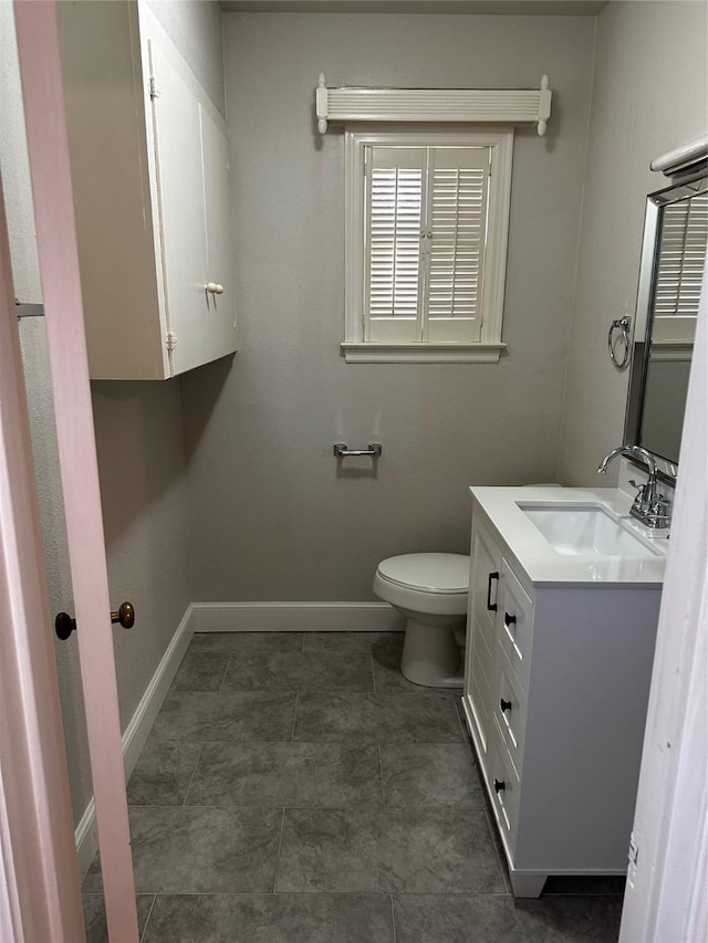 bathroom featuring vanity, toilet, and baseboards