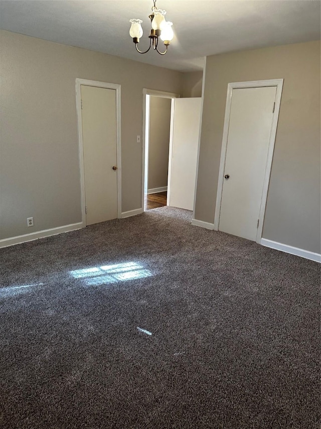 carpeted spare room with baseboards and an inviting chandelier