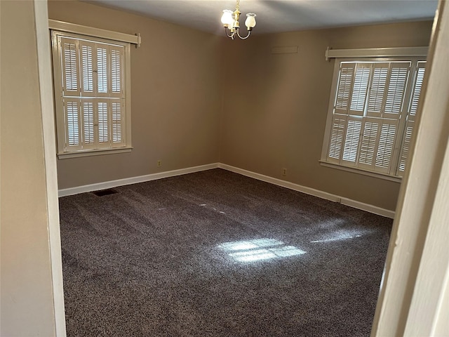 empty room featuring visible vents, baseboards, a notable chandelier, and dark carpet