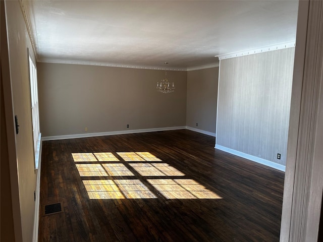 spare room featuring visible vents, a notable chandelier, ornamental molding, dark wood-style floors, and baseboards