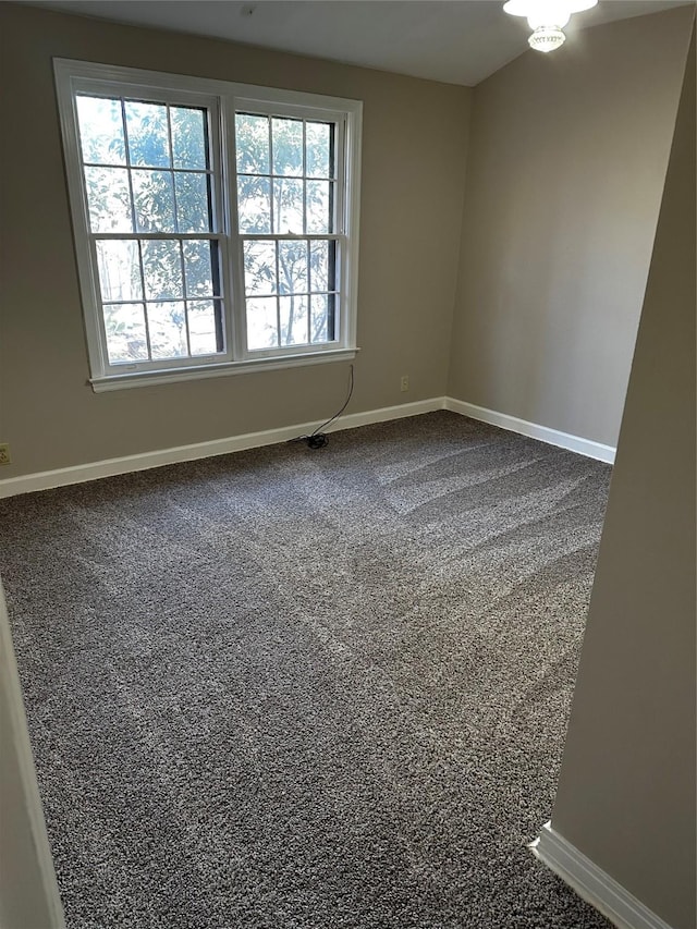 unfurnished room featuring baseboards and dark carpet