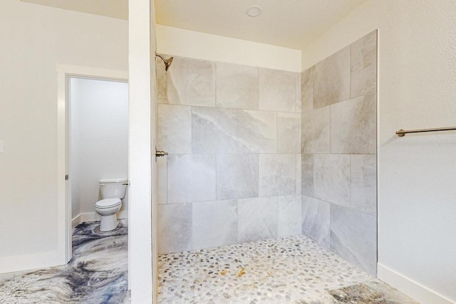 bathroom featuring toilet and a tile shower