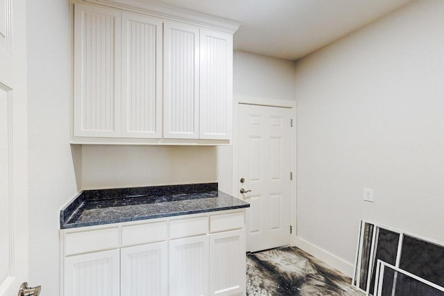 kitchen with light hardwood / wood-style floors, white cabinetry, and dark stone countertops