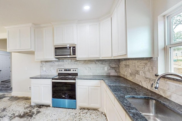 kitchen featuring tasteful backsplash, sink, white cabinets, and appliances with stainless steel finishes