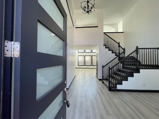 entrance foyer with a chandelier, wood-type flooring, and a towering ceiling