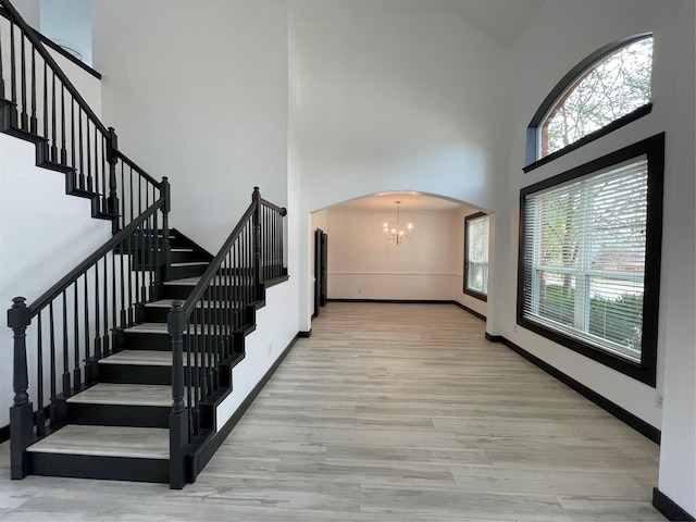 interior space with light hardwood / wood-style flooring, a high ceiling, and an inviting chandelier