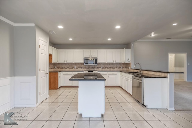 kitchen featuring stainless steel appliances, a kitchen island, sink, and white cabinets