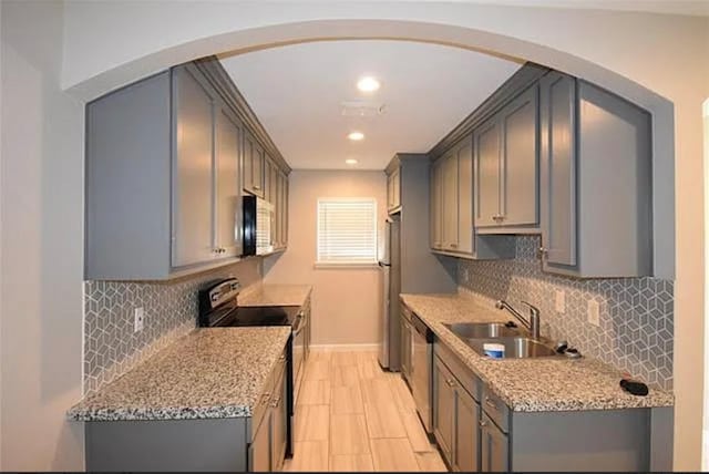 kitchen with gray cabinets, light stone countertops, sink, and black appliances