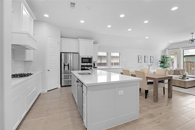 kitchen featuring stainless steel appliances, ceiling fan, sink, white cabinetry, and an island with sink