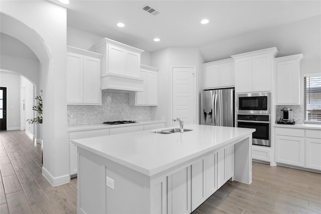 kitchen with white cabinets, sink, stainless steel appliances, and a kitchen island with sink