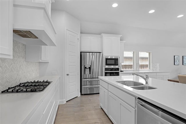 kitchen featuring white cabinetry, sink, stainless steel appliances, light hardwood / wood-style flooring, and custom exhaust hood