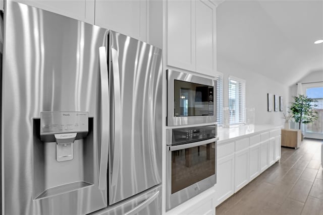 kitchen with white cabinets, plenty of natural light, appliances with stainless steel finishes, and vaulted ceiling