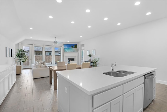 kitchen with dishwasher, a center island with sink, white cabinets, sink, and ceiling fan