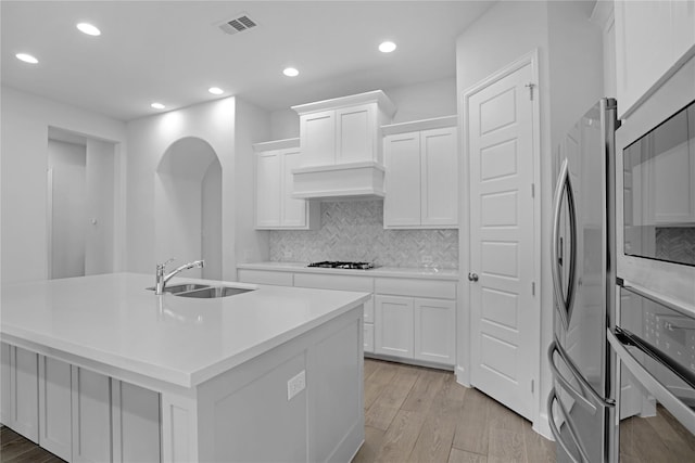 kitchen with a kitchen island with sink, sink, white cabinets, and appliances with stainless steel finishes