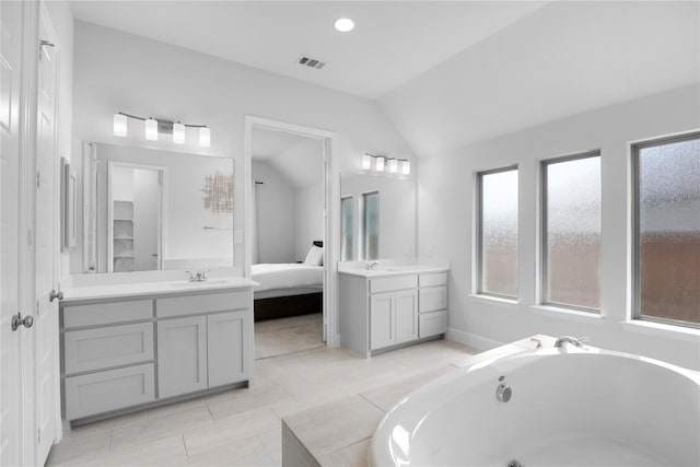 bathroom featuring tile patterned flooring, a bath, vanity, and vaulted ceiling