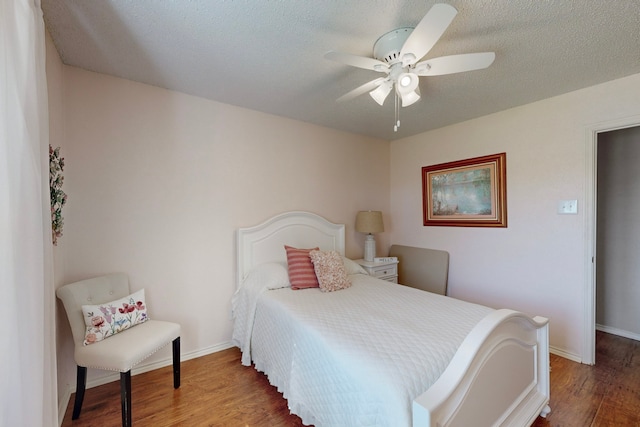 bedroom with ceiling fan, dark hardwood / wood-style flooring, and a textured ceiling