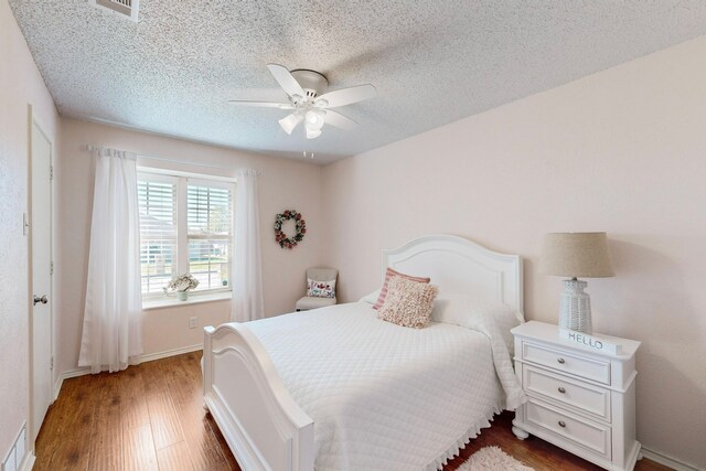 bedroom with ceiling fan, dark hardwood / wood-style flooring, and a textured ceiling