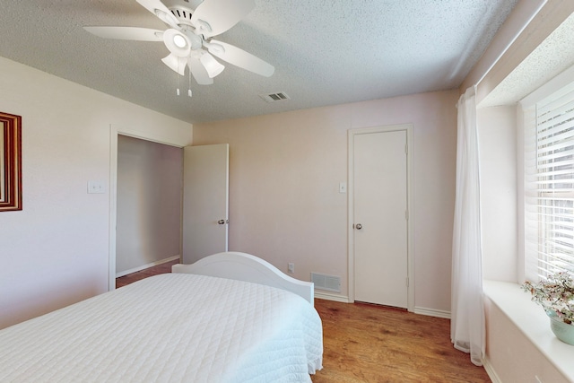 bedroom with a textured ceiling, light hardwood / wood-style floors, and ceiling fan