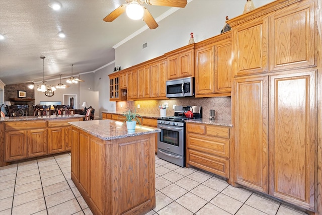 kitchen with stainless steel appliances, a ceiling fan, crown molding, a center island, and backsplash