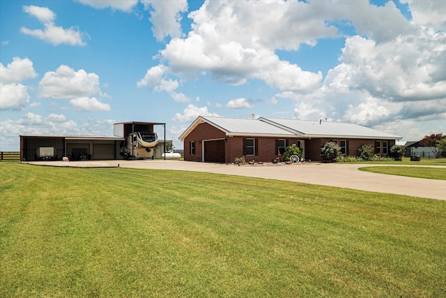 ranch-style house featuring concrete driveway, a front yard, a garage, and an outbuilding