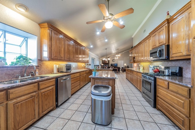 kitchen with appliances with stainless steel finishes, a sink, ceiling fan, crown molding, and a kitchen island